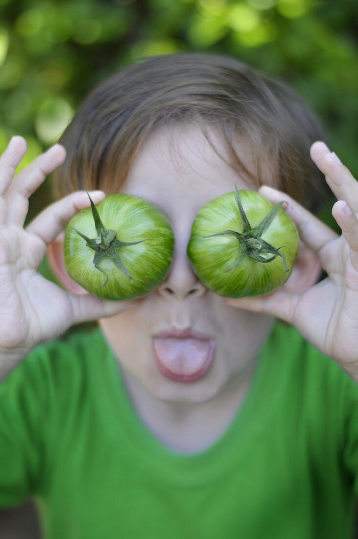 Child playing with green tomatoes