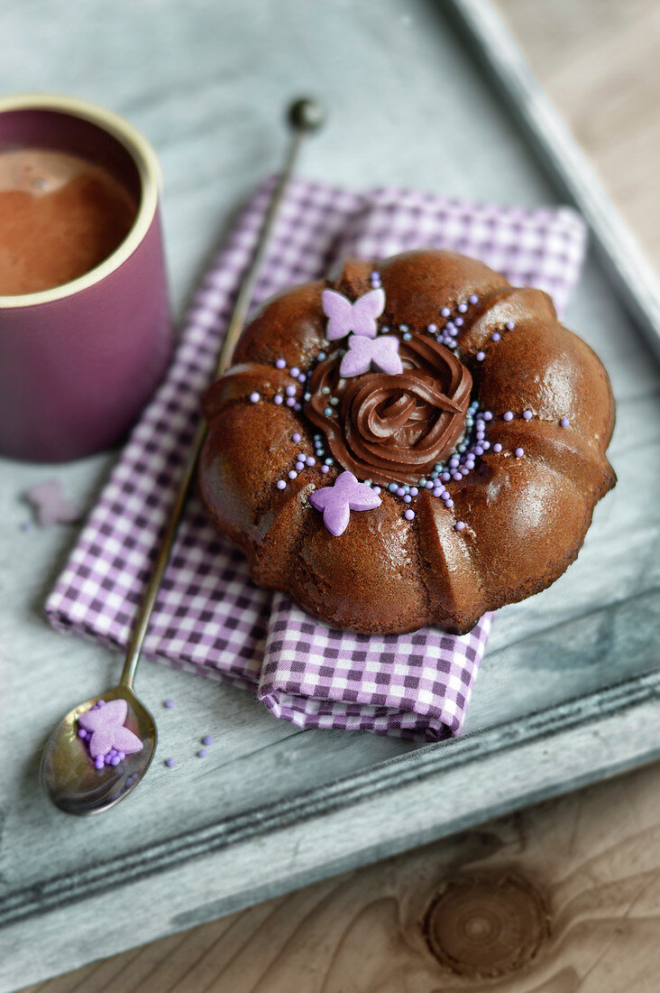 Small chocolate cake with a pink decoration and a cup of expresso