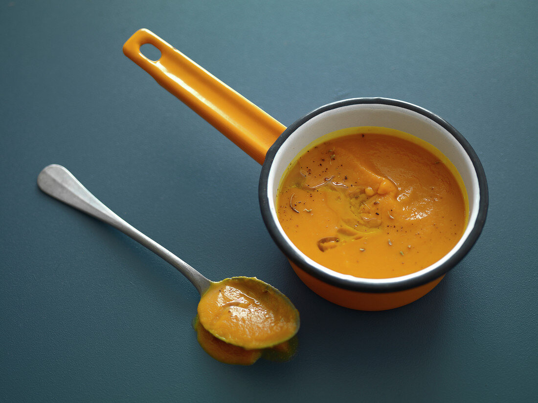 Saucepan and large spoonful of pumpkin soup