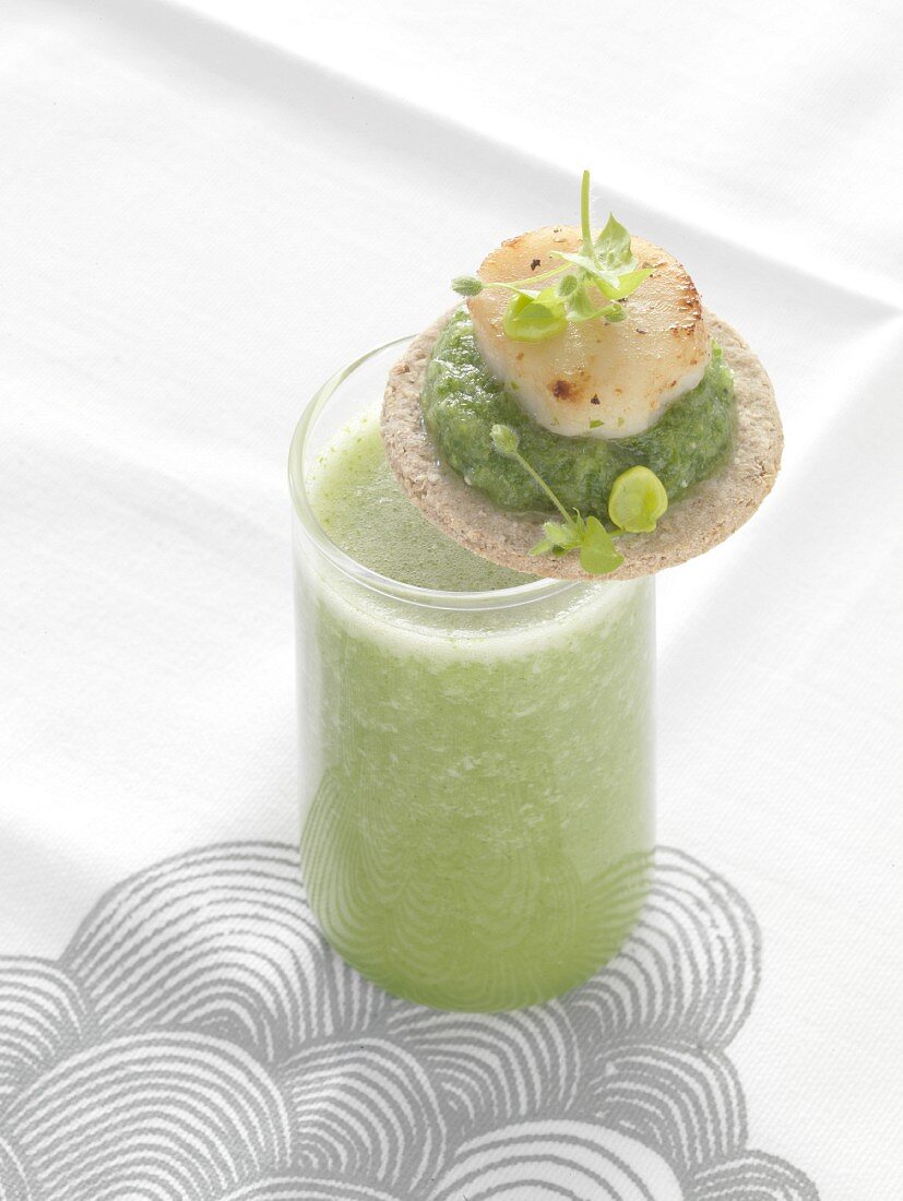 Green gazpacho with a cracker garnished with mashed peas and scallops