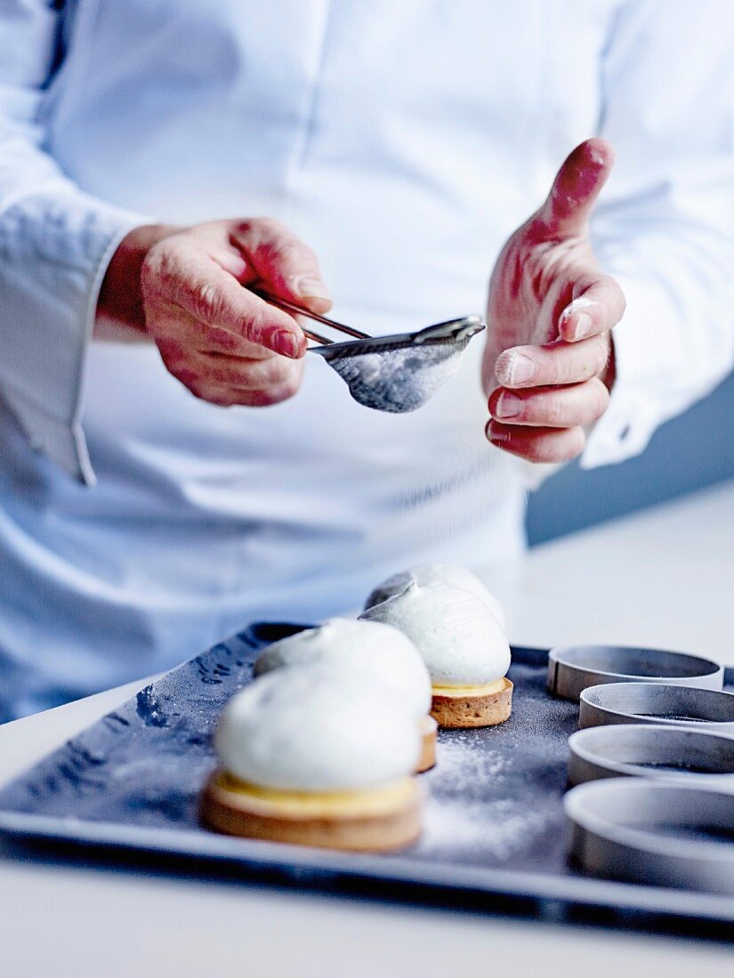 Sprinkle powdered sugar on lemon meringue cream tarts