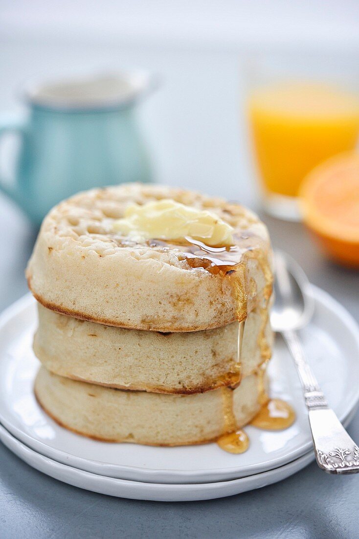 Crumpet (englische Hefebrötchen) mit Butter und Honig zum Frühstück