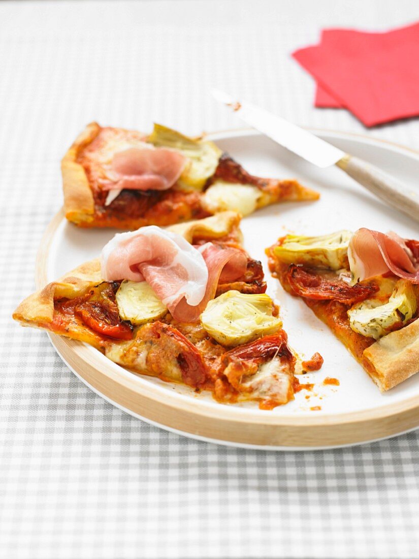 Pizza mit Artischocken, Tomaten und Rohschinken