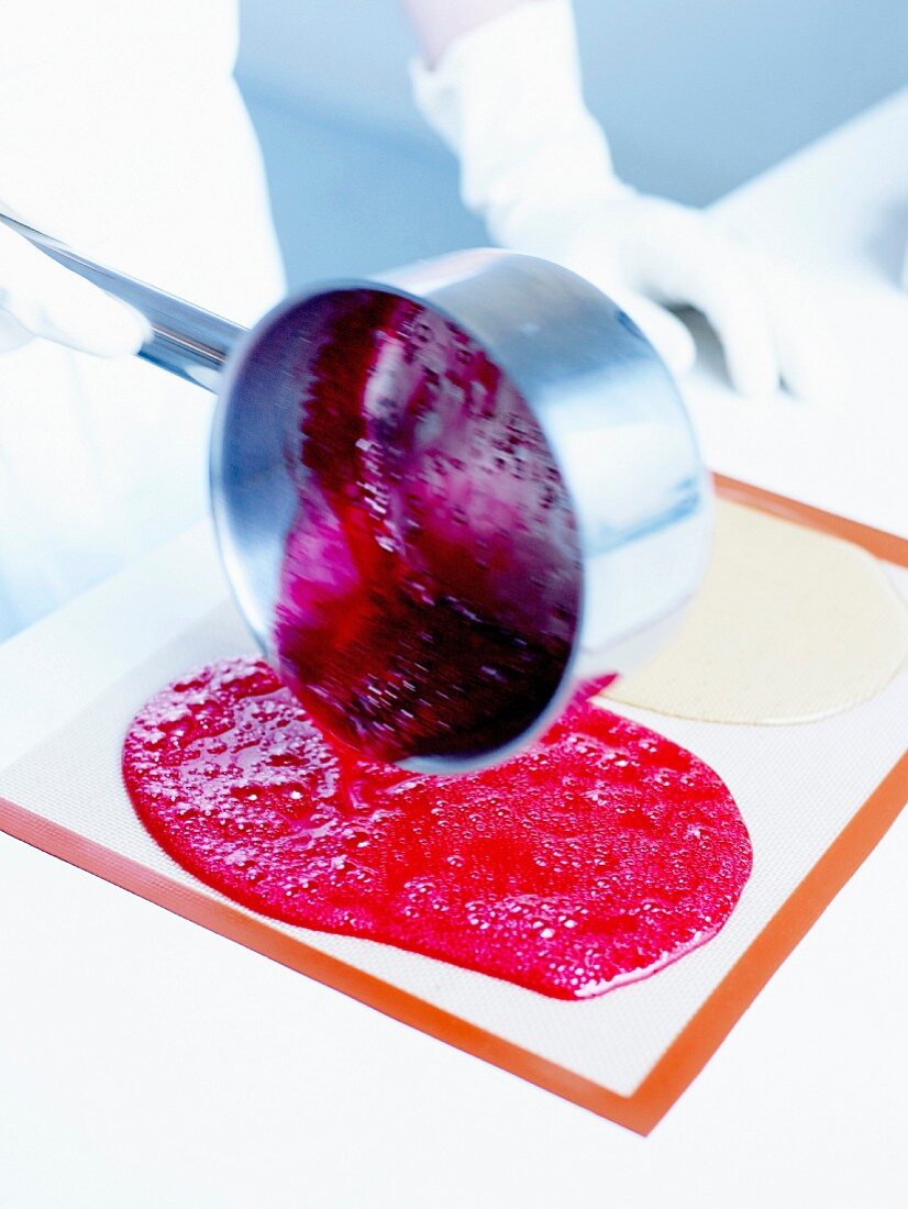 Pouring the raspberry-flavored preparation next to the plain preparation on a non-stick mat