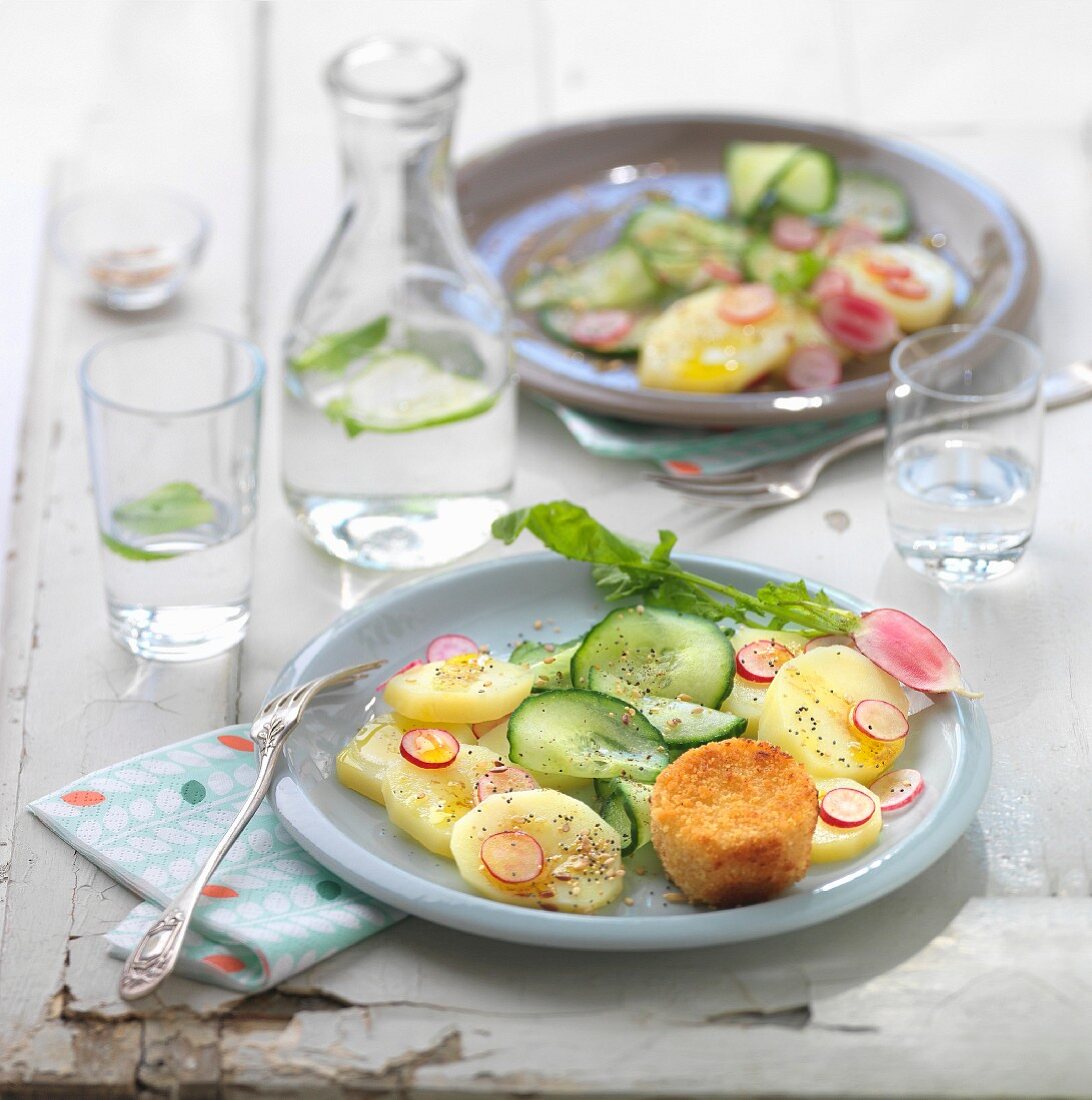 Salat mit Gurken, Kartoffeln, Radieschen und paniertem Ziegenkäse