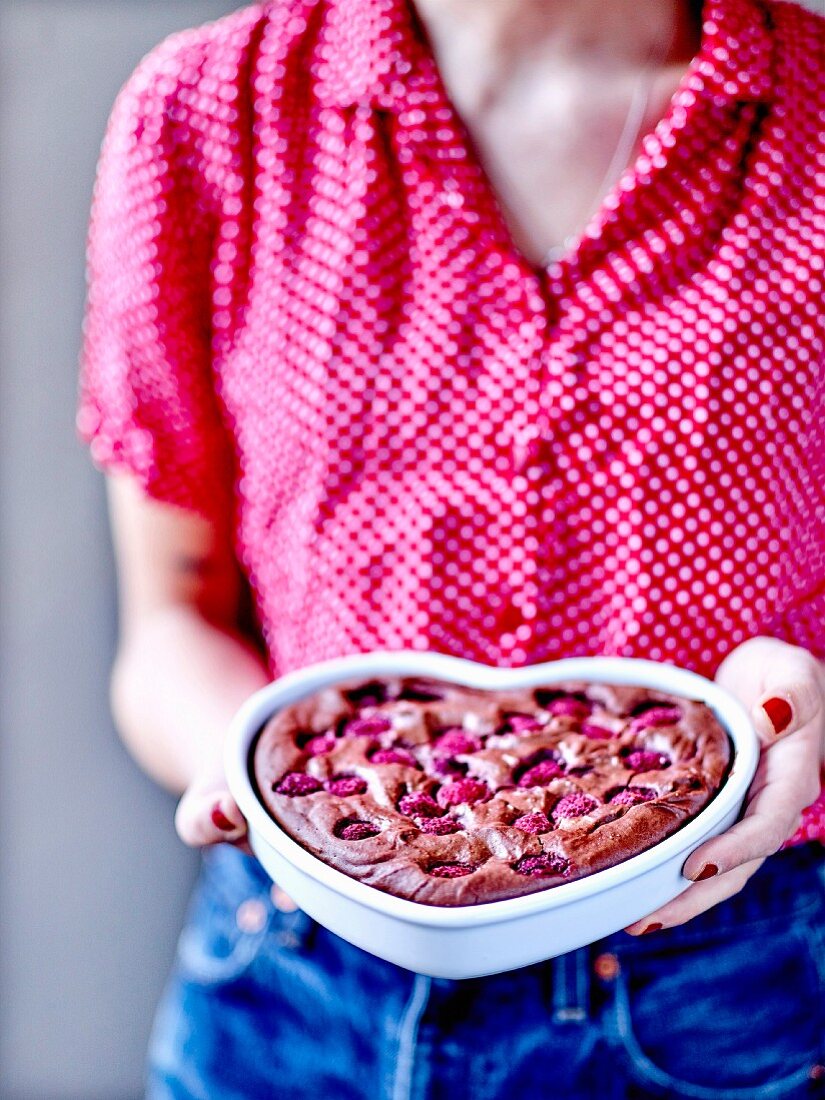 Woman holding a tofu, chocolate and raspberry heart-shaped cake