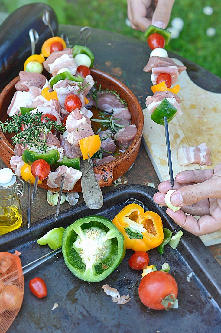 Preparing pork and vegetable brochettes on the barbecue