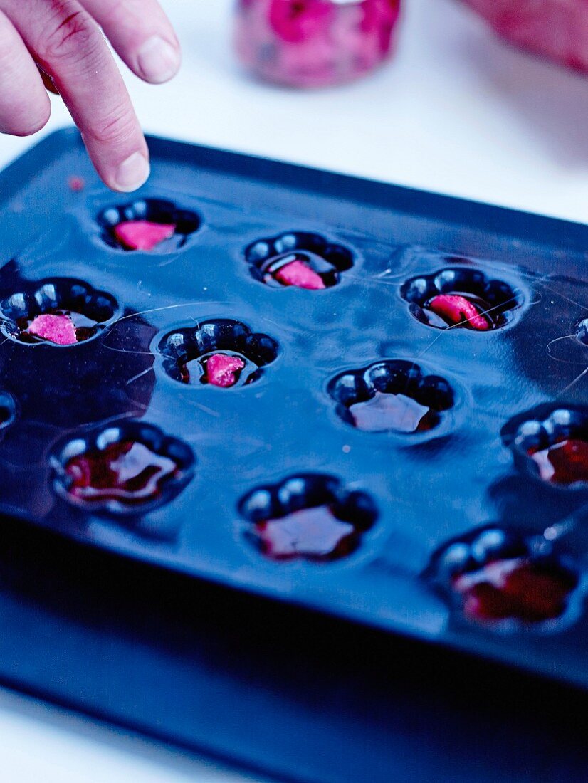 Placing a crystallized rose petal on each full flower-shaped silicone mold