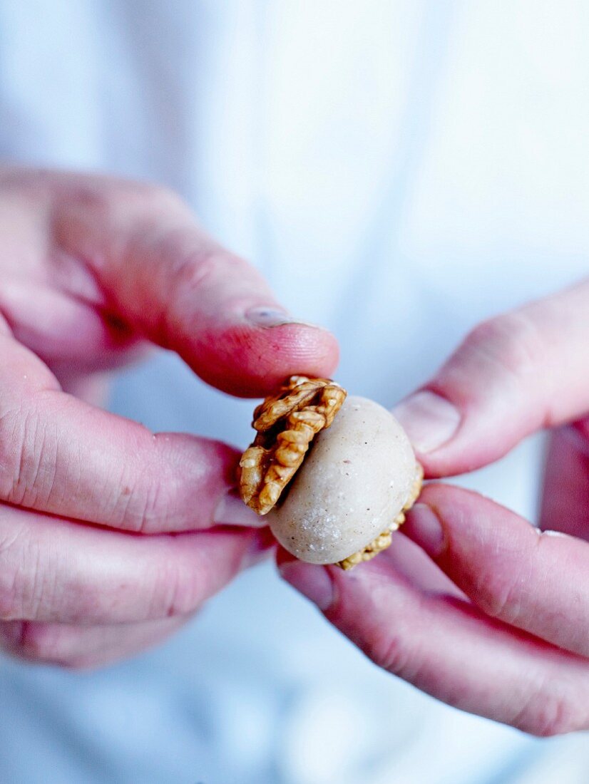 Making a cinnamon-almond paste bite between walnut halves