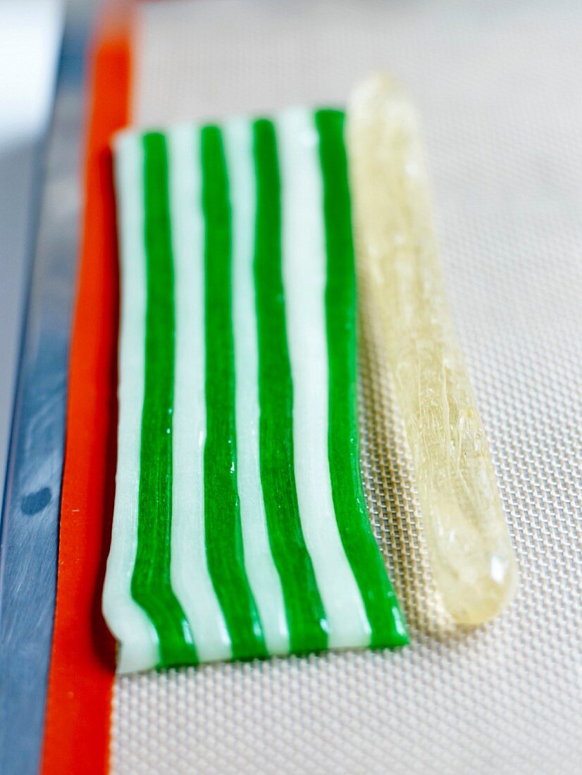 Bergamotten-Berlingots herstellen: Die durchsichte Zuckerpastenwurst neben die 8 Streifen gefärbte Zuckerpaste legen
