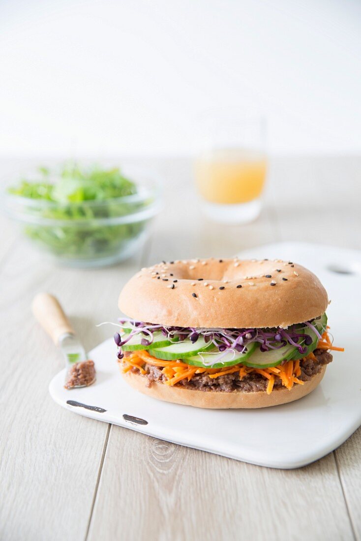 Tapenade, carrot, cucumber and radish sprout vegetarian bagel sandwich