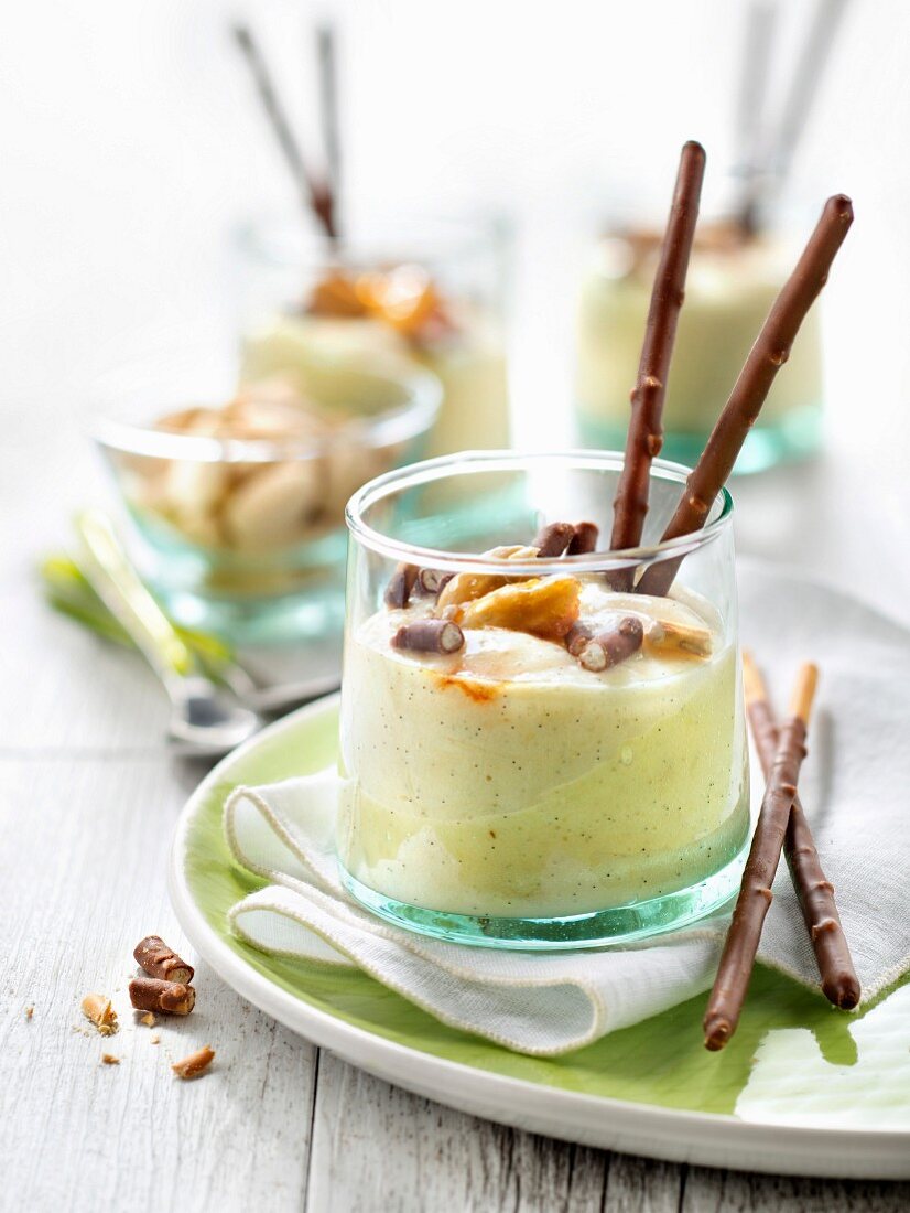 Vanillemousse mit karamellisierten Mandelsplittern und Schoko-Mikadostäbchen im Glas