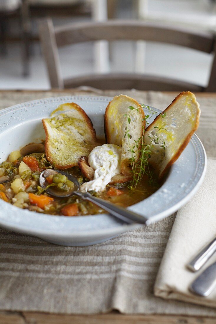 Minestrone with a poached egg and thin slices of bread