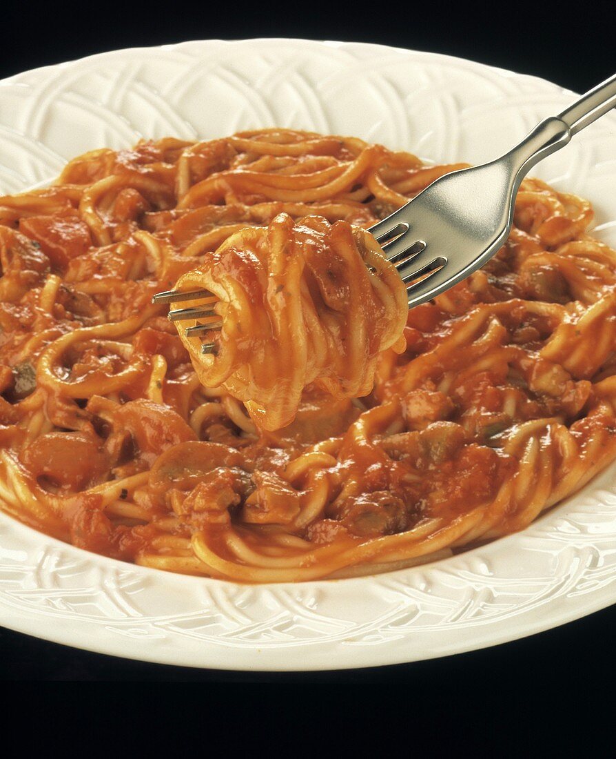 Spaghetti mit Tomatensauce auf weißem Teller & Gabel