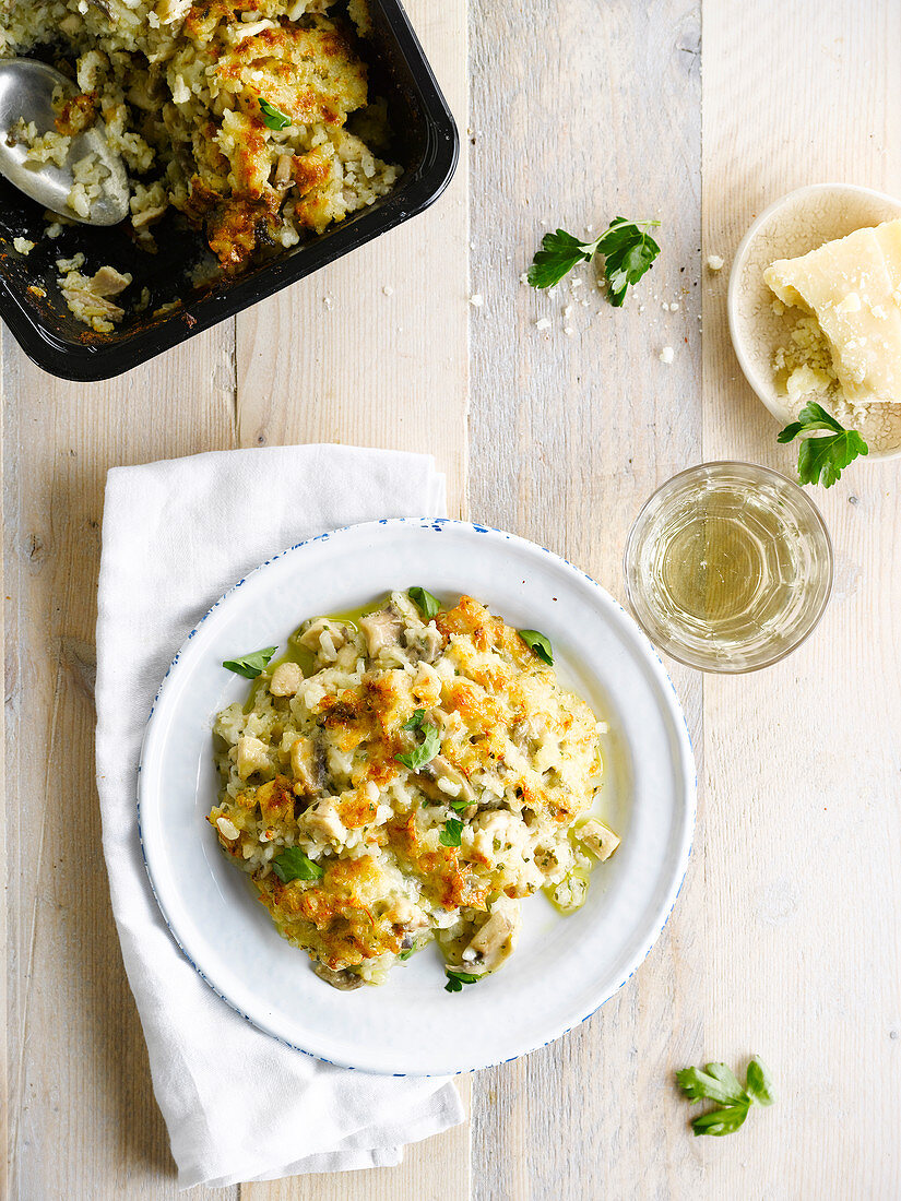 Portion Risotto-Gratin mit Huhn, Pilzen und Parmesan.