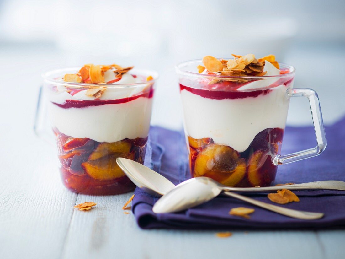 Sahnedessert mit Zwetschgen in Sirup, Johannisbeersauce und karamellisierten Mandelblättchen