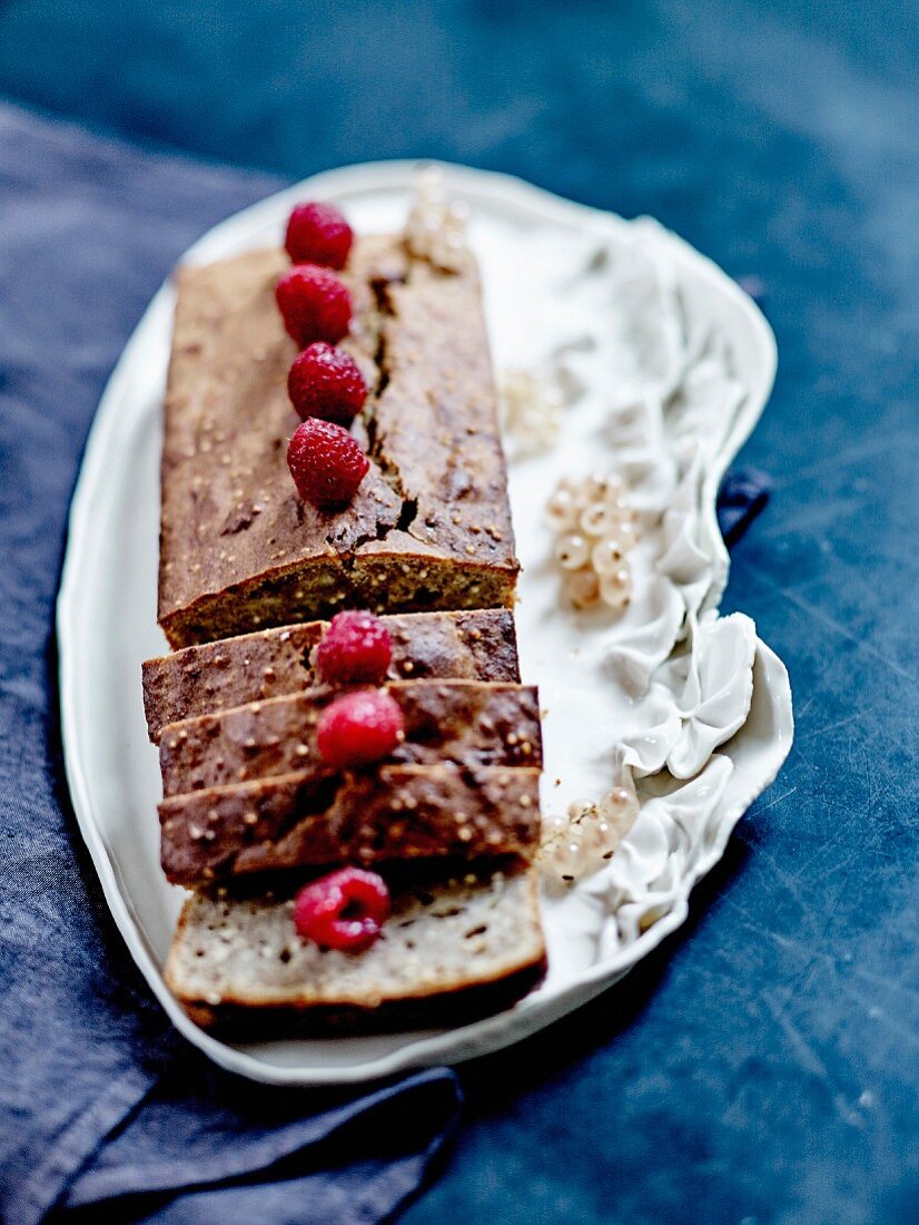 Crisp banana and millet cake decorated with raspberries and white currants