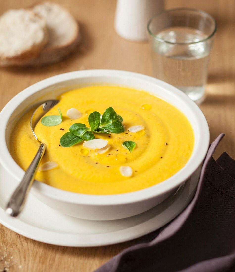Gelbe Karotten-Kürbis-Cremesuppe mit Mandeln und Feldsalat