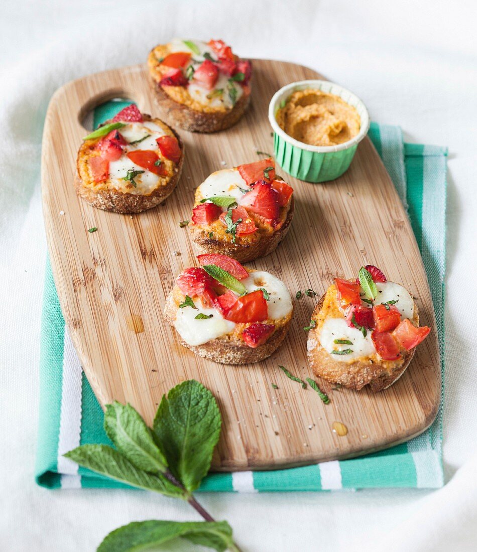 Creamed pepper, mozzarella and mixed tomato-strawberry crostinis with mint