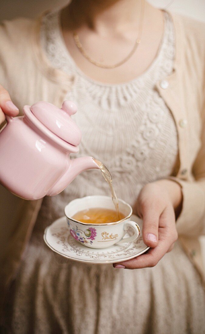 Woman serving a china cup of tea