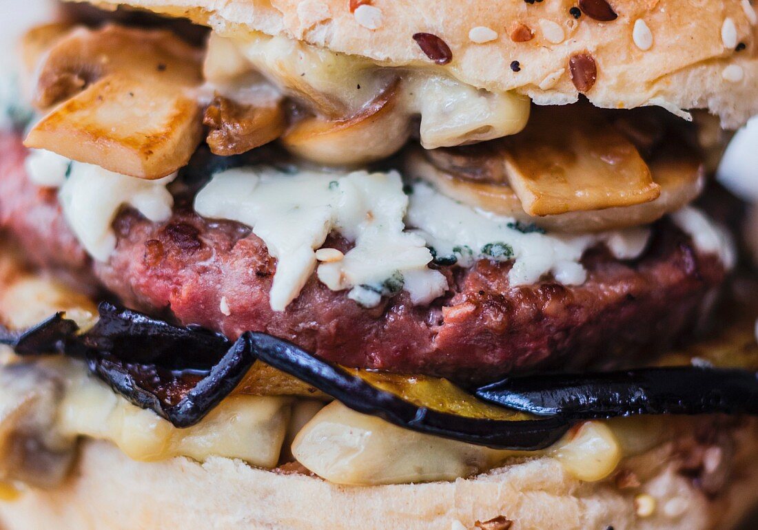 Nahaufname von einem Rinderhackburger mit Aubergine, Roquefort und Champignons