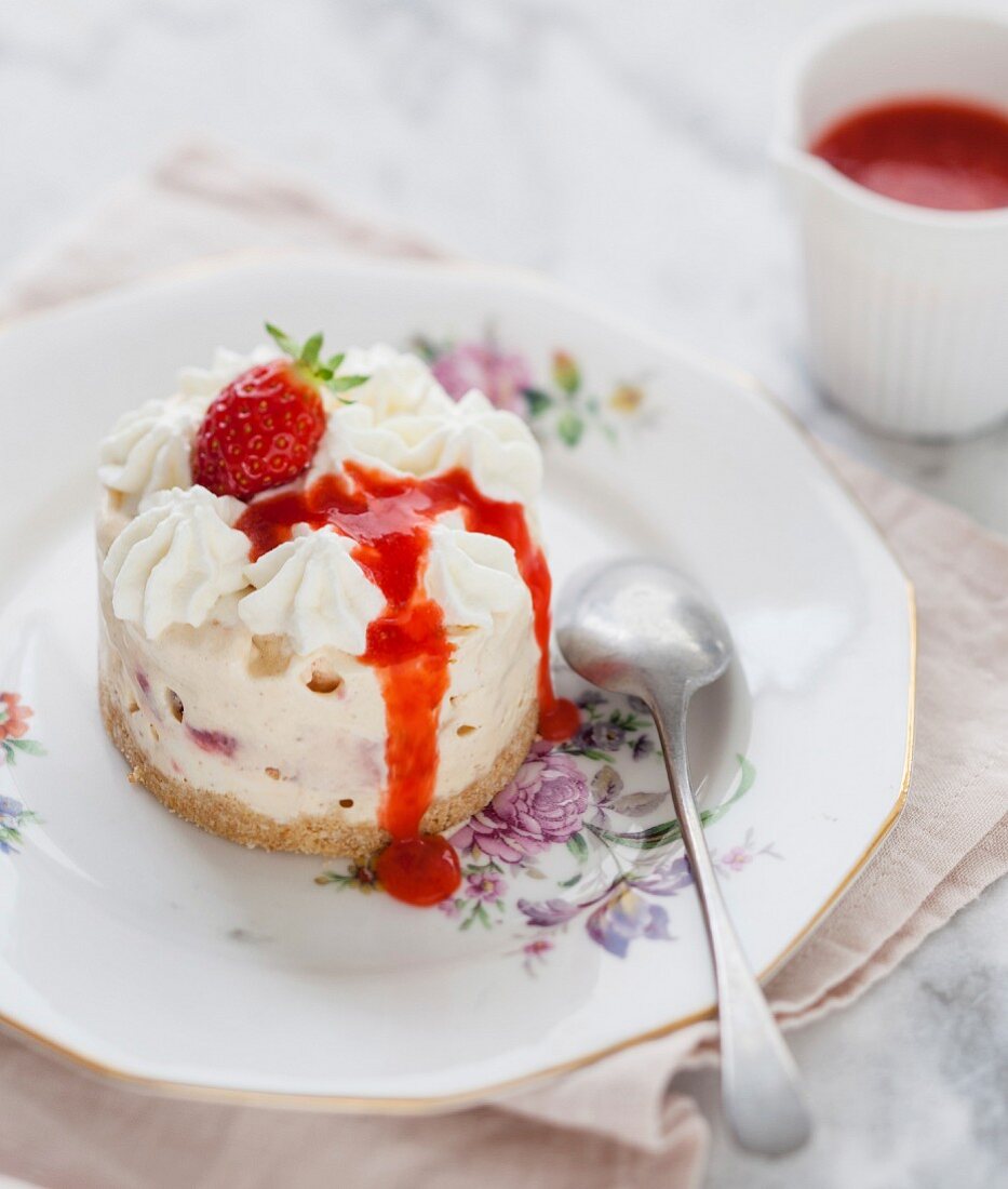 Small iced meringue cheesecake with fresh strawberries and coulis