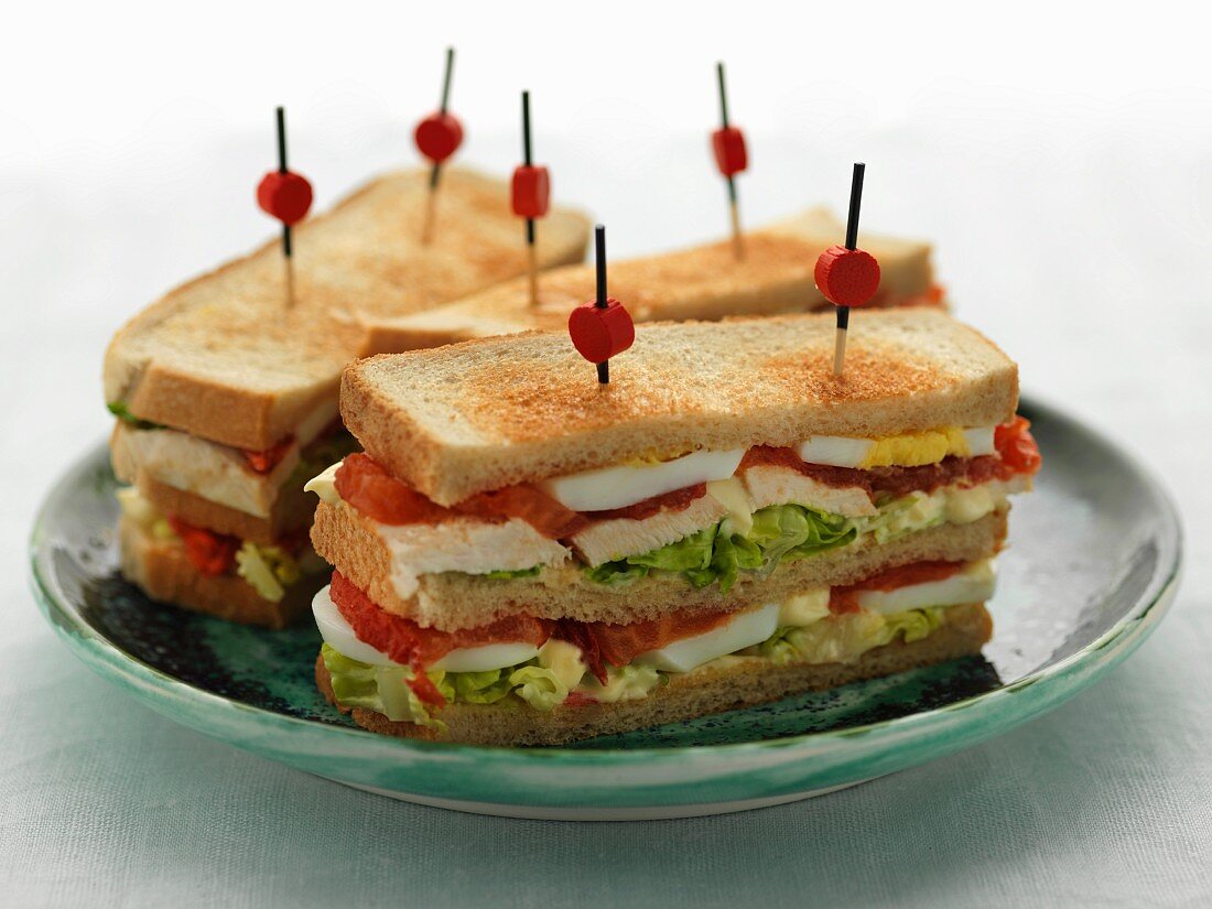 Clubsandwiches mit Hähnchen, Tomaten, Salatblättern und hartgekochtem Ei