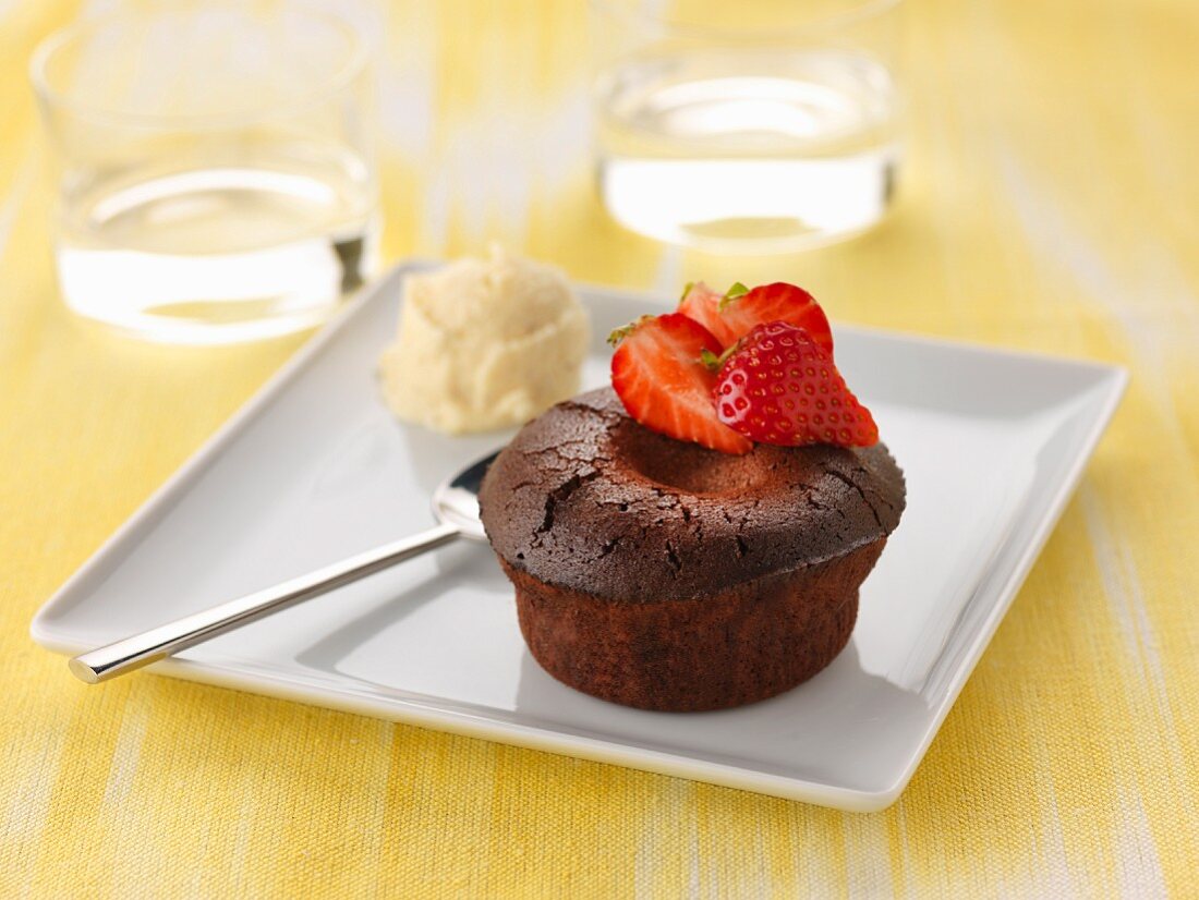 Individual chocolate runny pudding with fresh strawberries and vanilla ice cream