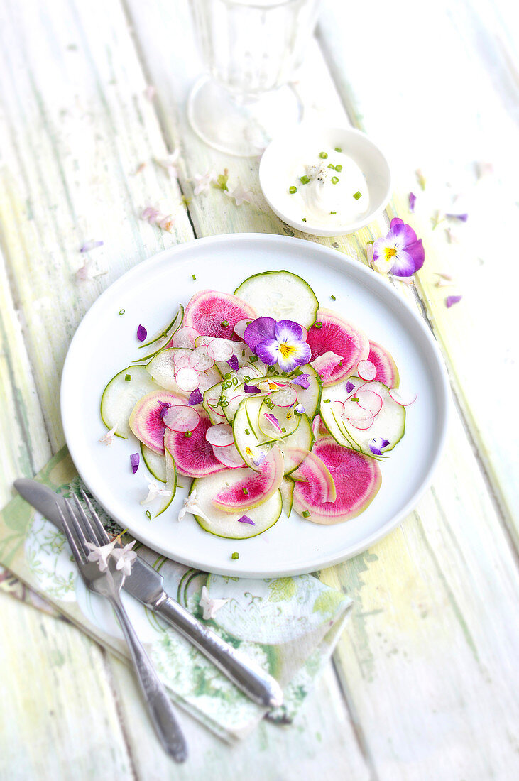 Salat mit Gurken, weißem und roten Rettich und Essblüten zum Osterfest