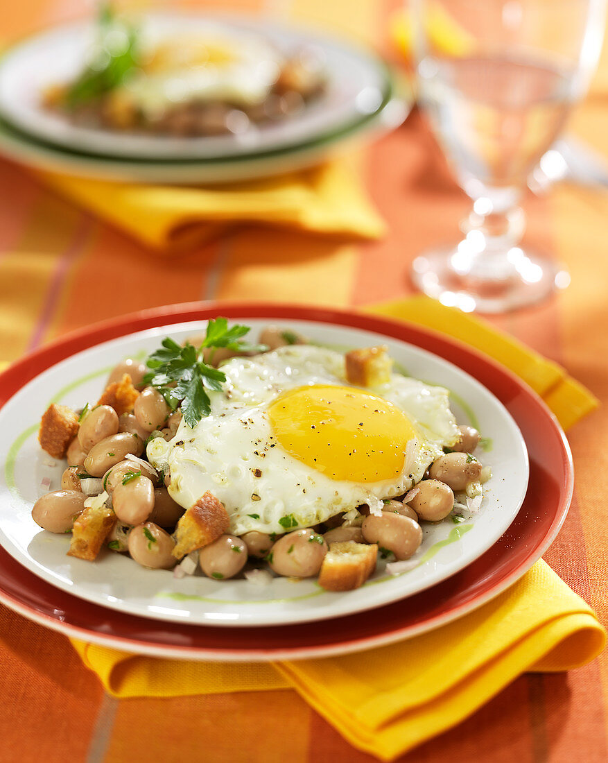 White haricot bean salad topped with a fried egg