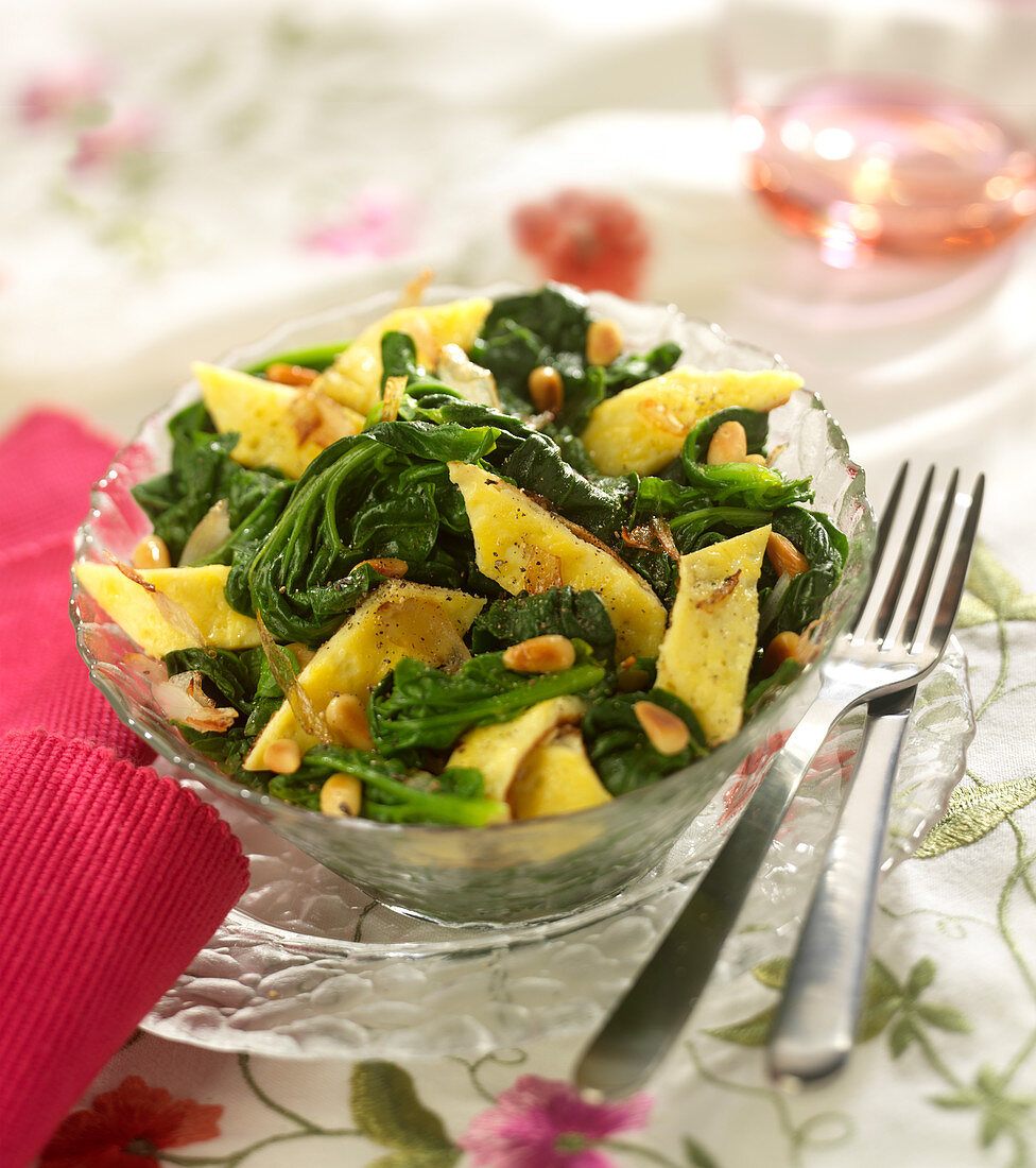 Pan-fried spinach with omelette and grilled pine nuts