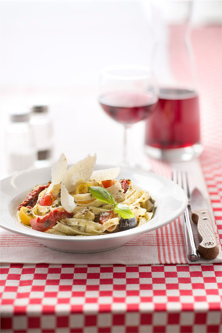 Tagliatelle mit Pesto, eingelegten Tomaten, Kirschtomaten, Oliven und Parmesanspänen