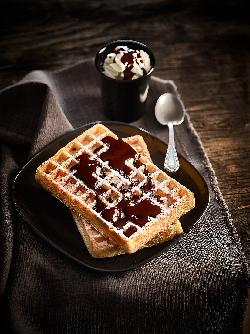 Brussels waffles sprinkled with icing sugar,chocolate sauce and whipped cream