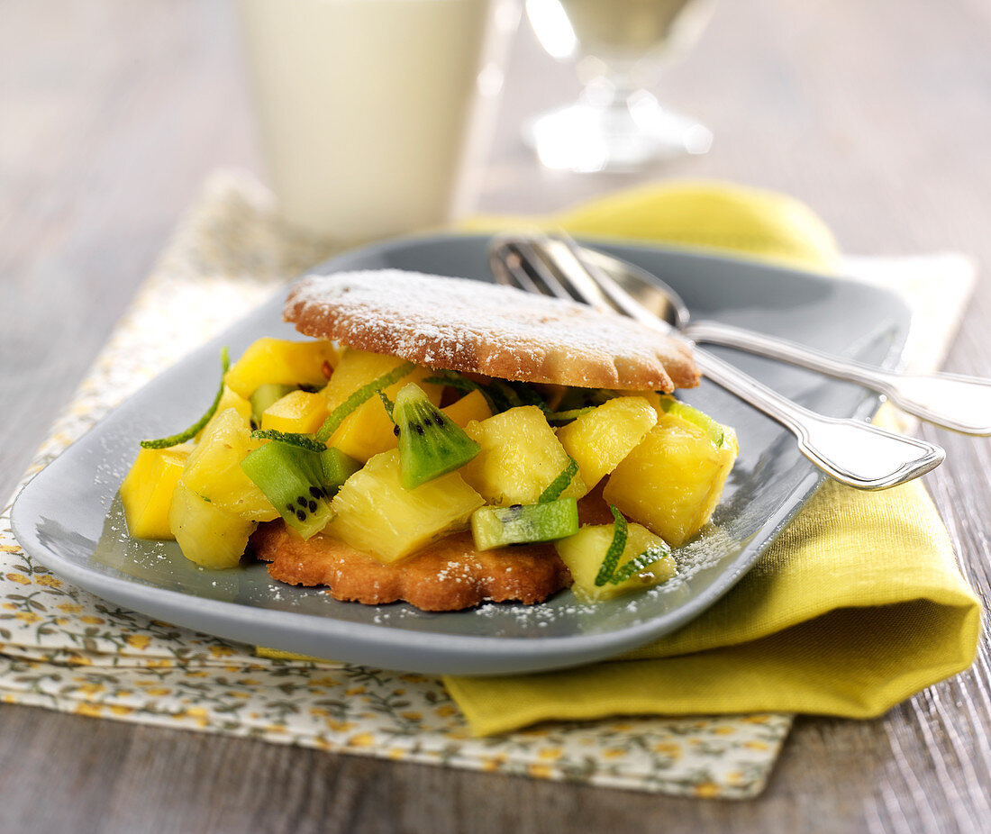 Keks-Sandwich mit fruchtiger Füllung aus Ananas, Kiwi und Limettenzesten