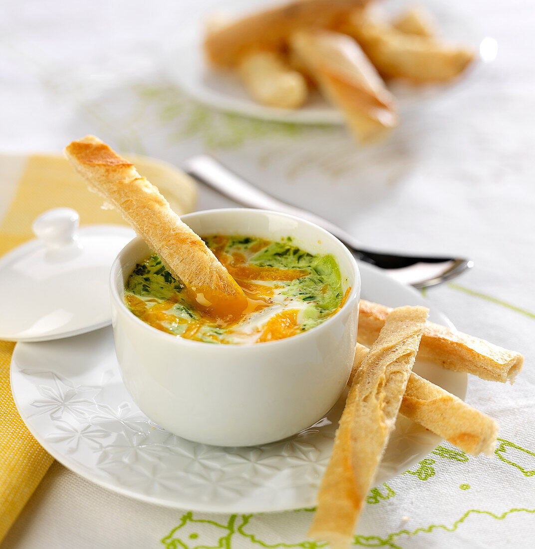 Shirred eggs with herbs and Mimolette, bread fingers