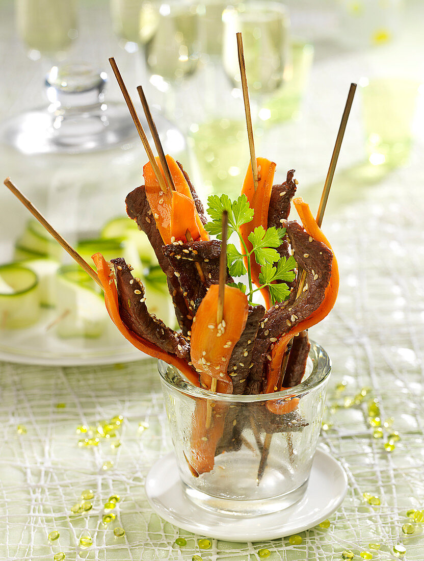 Marinated beef brochettes and thin strips of carrots with sesame seeds