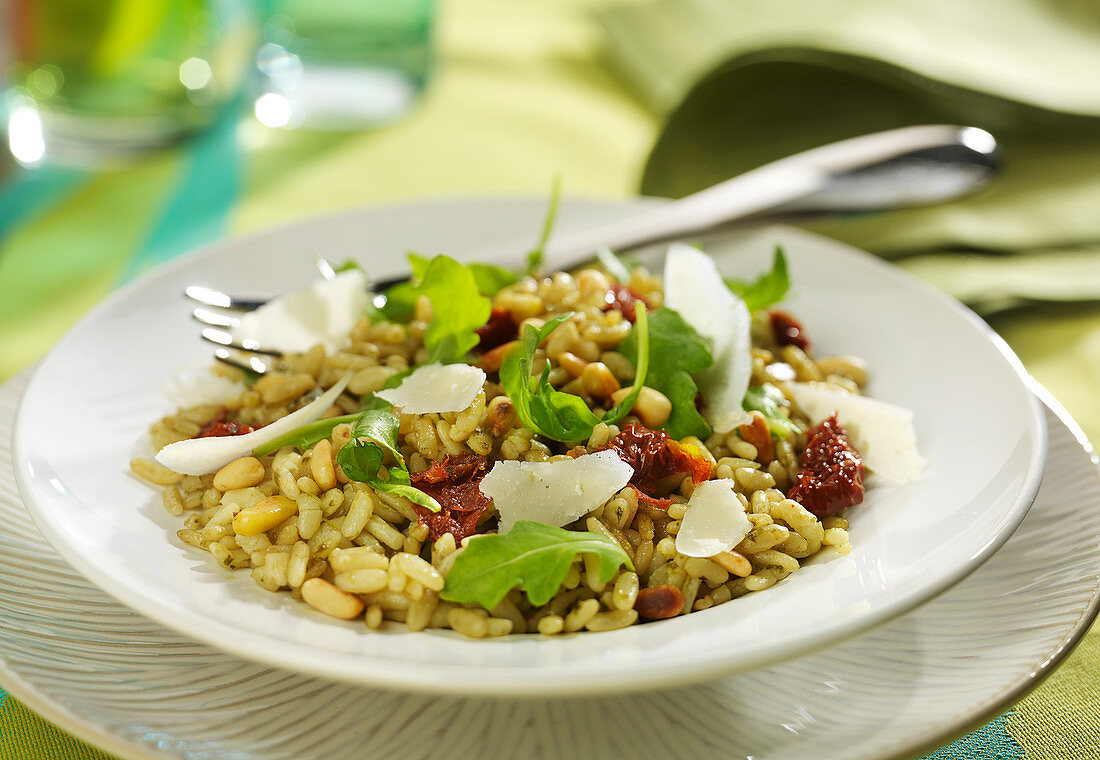 Reissalat mit eingelegten Tomaten, Rucola, Pinienkernen und Parmesanspänen