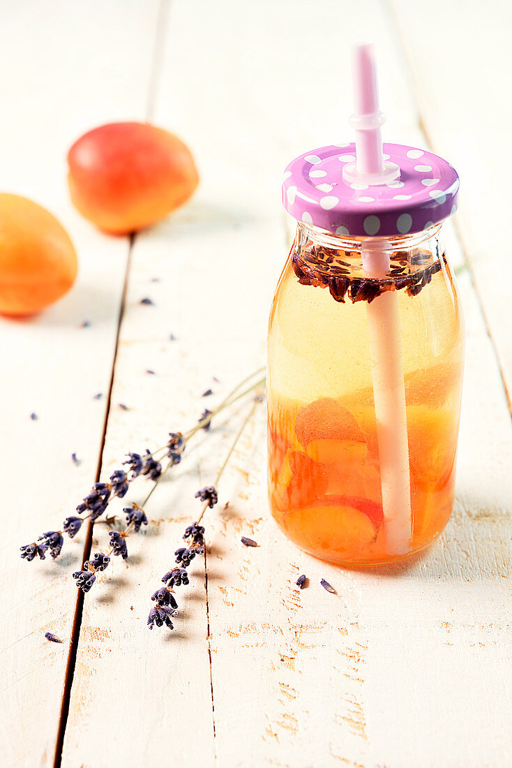 Aromatisiertes Wasser mit Aprikosen und Lavendel in einem Fläschchen mit Deckel und Strohhalm