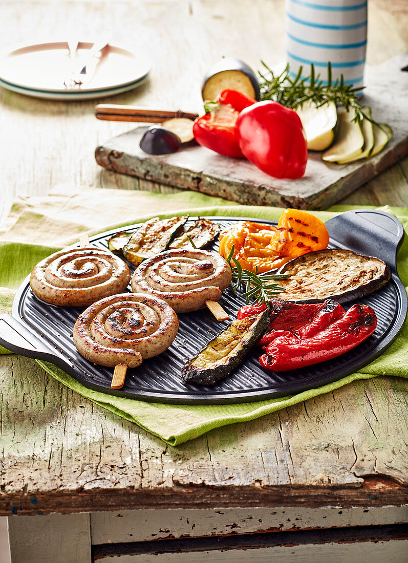 Rolled sausages on a knife and vegetables a la plancha