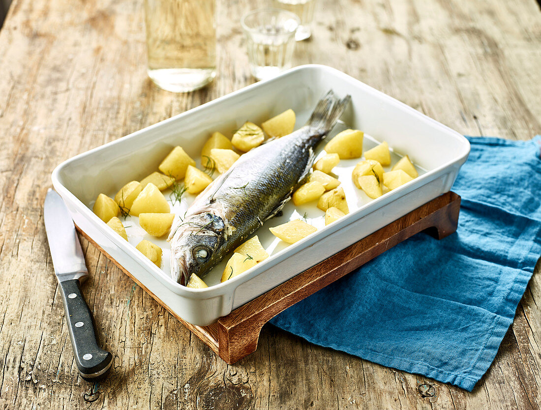 Preparing sea bass and potatoes to be oven-baked