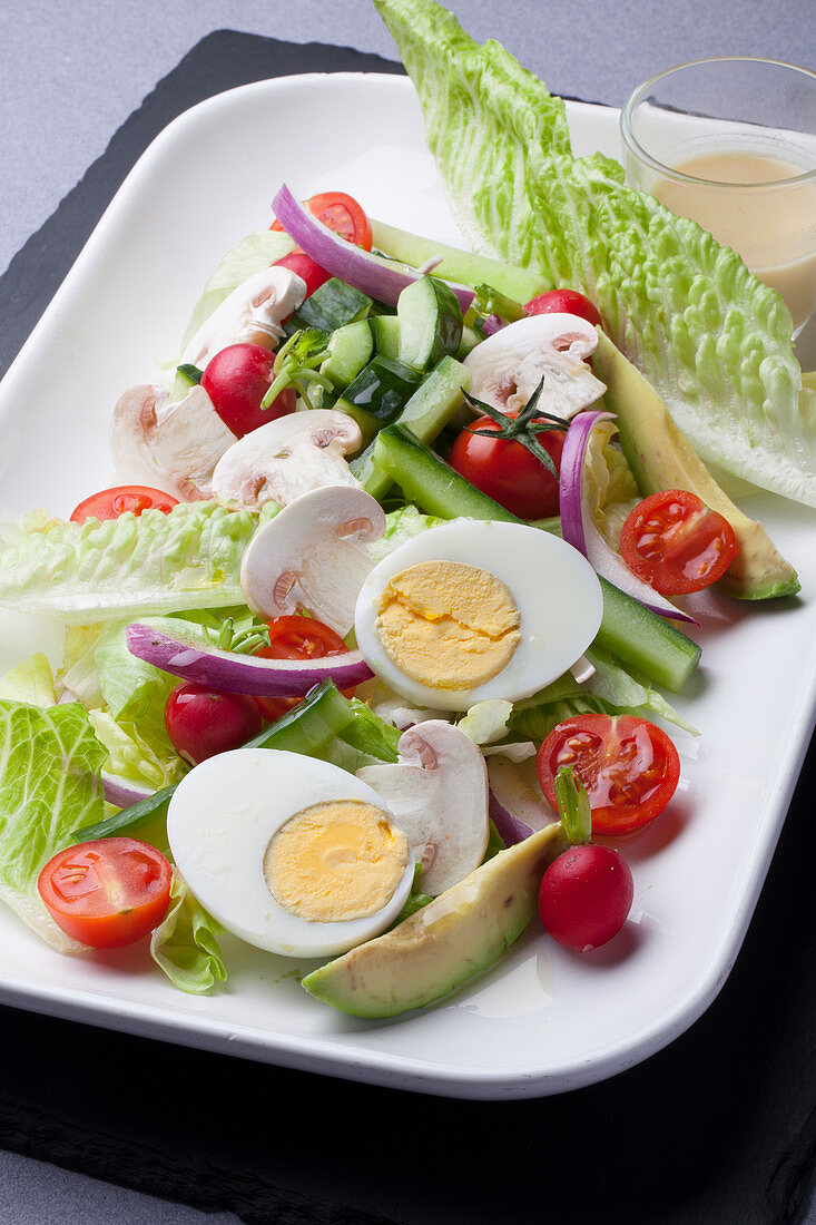 Salat mit hartgekochtem Ei, Gurke, Kirschtomaten, Champignons, Radieschen und Avocado