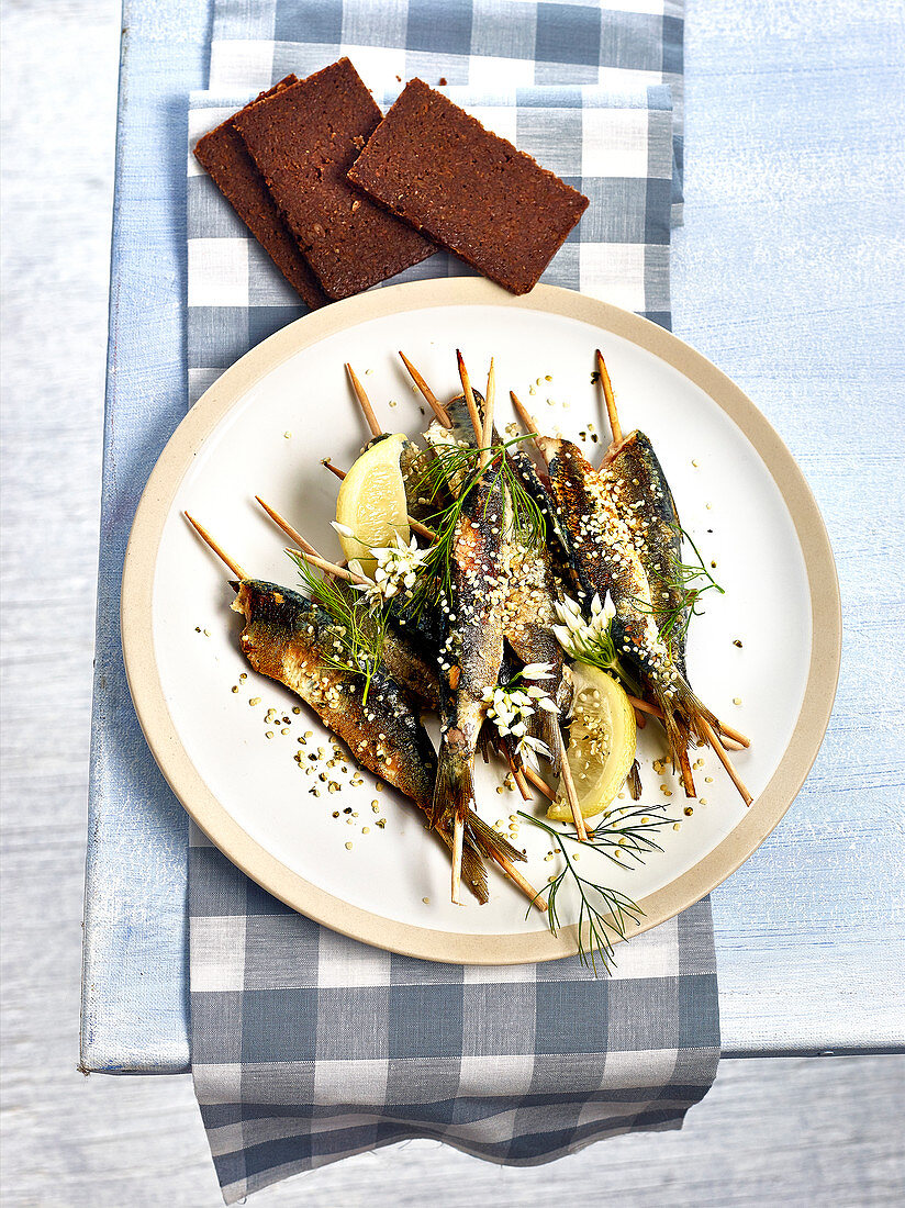 Gegrillte Sardinenspiesse mit Zitrone, Dill, Bärlauchblüten und Hanfsamen, dazu Roggenvollkornbrot