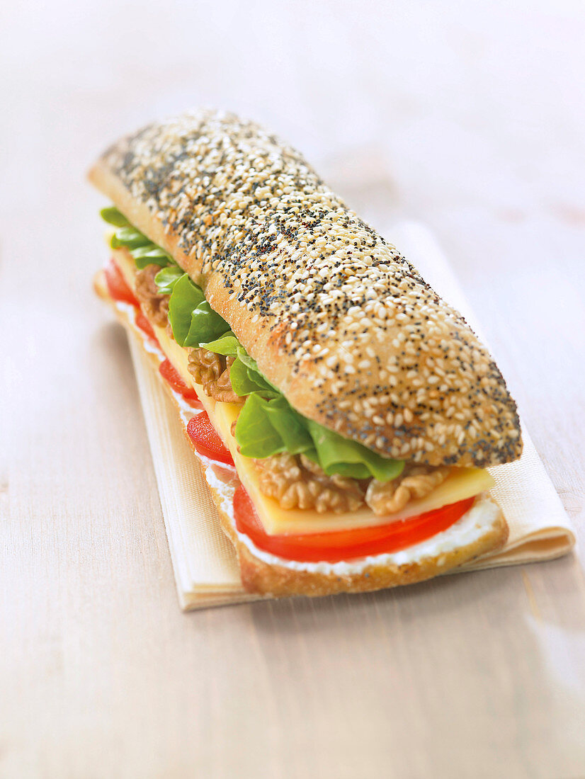 Mohn-Sesam-Brot-Sandwich mit Frischkäse, Tomaten, Emmentaler, Walnüssen und Salat