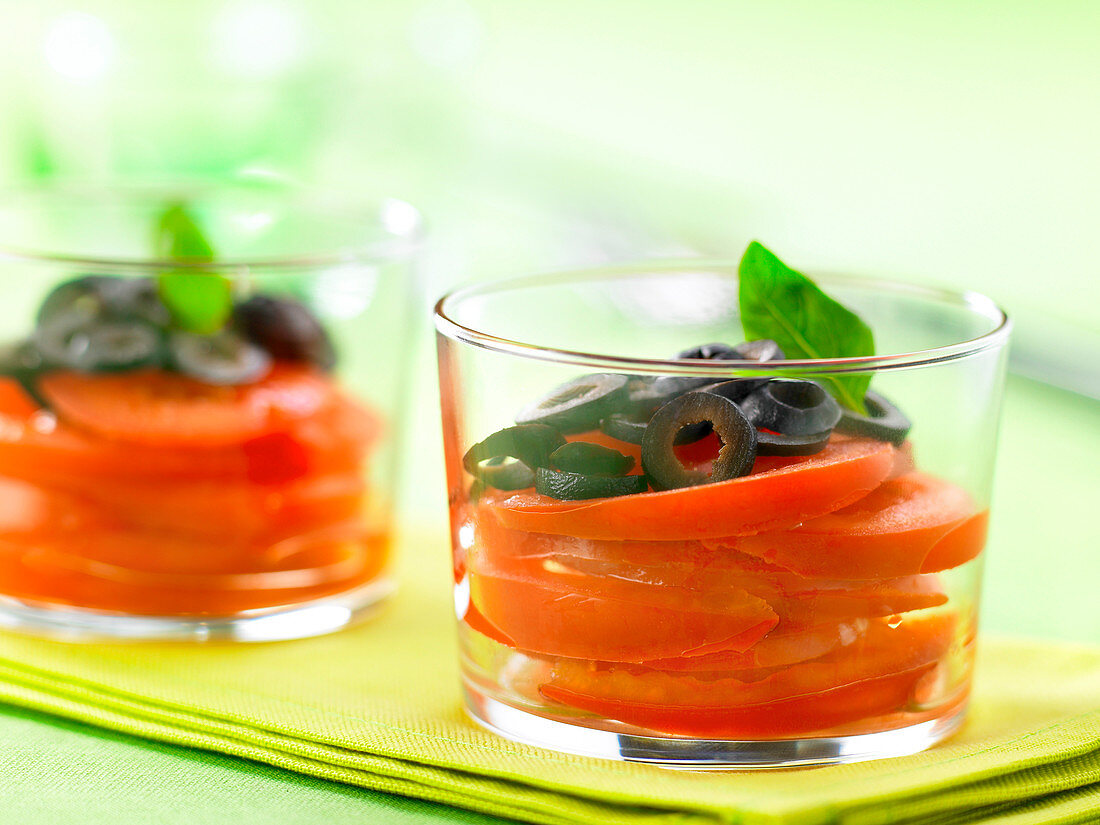 Tomatensalat mit schwarzen Oliven und Basilikum, im Glas serviert