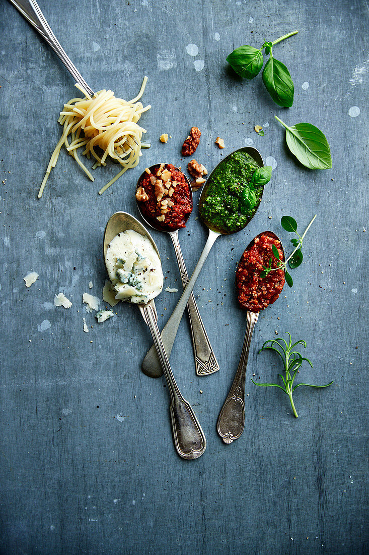 Nudelsaucen auf Löffeln: Käsesauce, Chili-Tomatensauce, Pesto und Bolognese