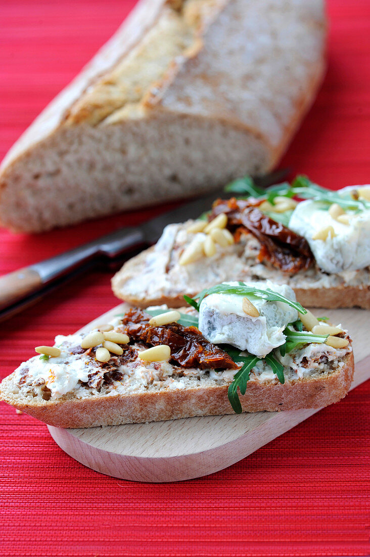 Belegtes Brot mit eingelegten Tomaten, Pinienkernen und Rucola