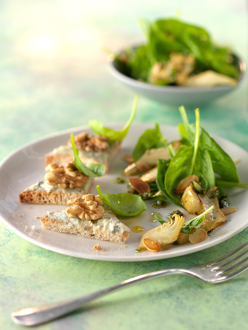 Baby spinach and sliced artichoke salad with Roquefort butter on toasts