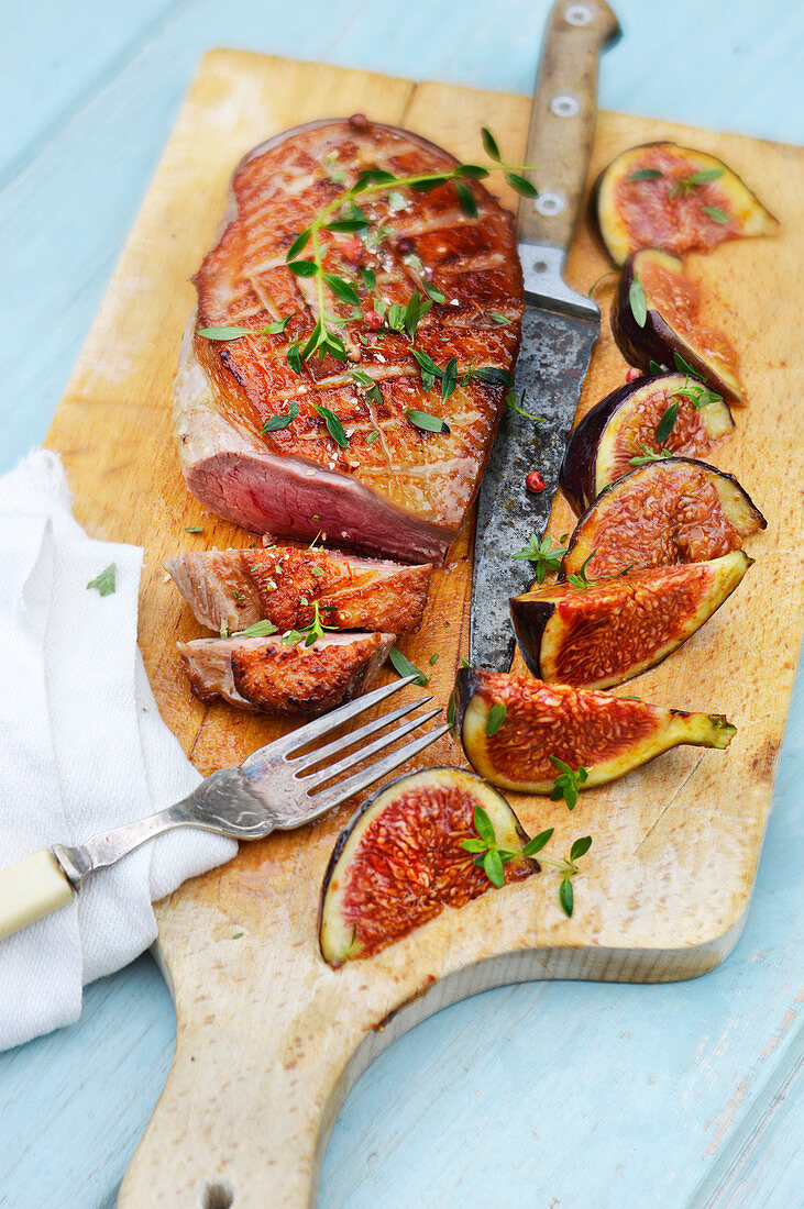 Roast duck breast with figs on wooden board