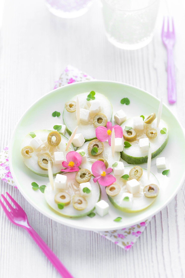 Erfrischender Salatteller mit Gurken, Feta, Oliven und Essblüten