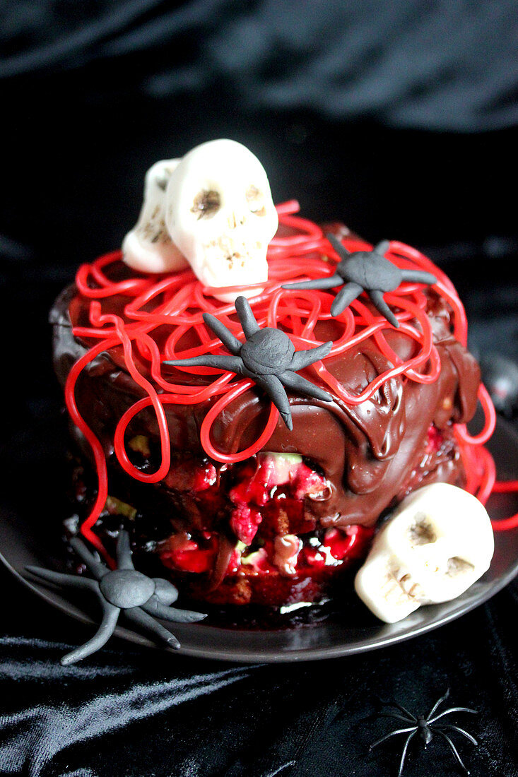 Chocolate,pistachio cream and cherries glac? cake decorated with sugar paste sculls and spaghetti sweets